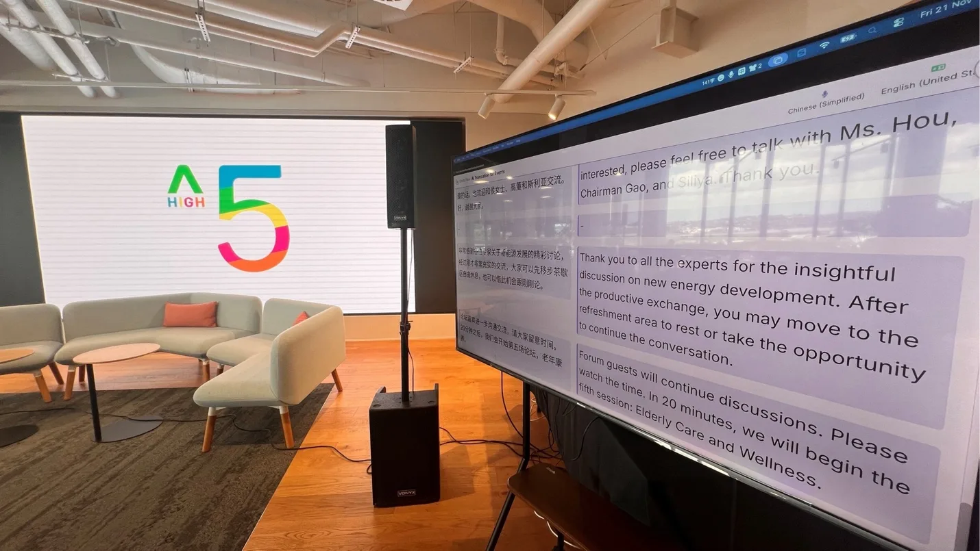 The HIGH 5 conference with the source speech and its live English translation shown side by side on the room’s main screen.
