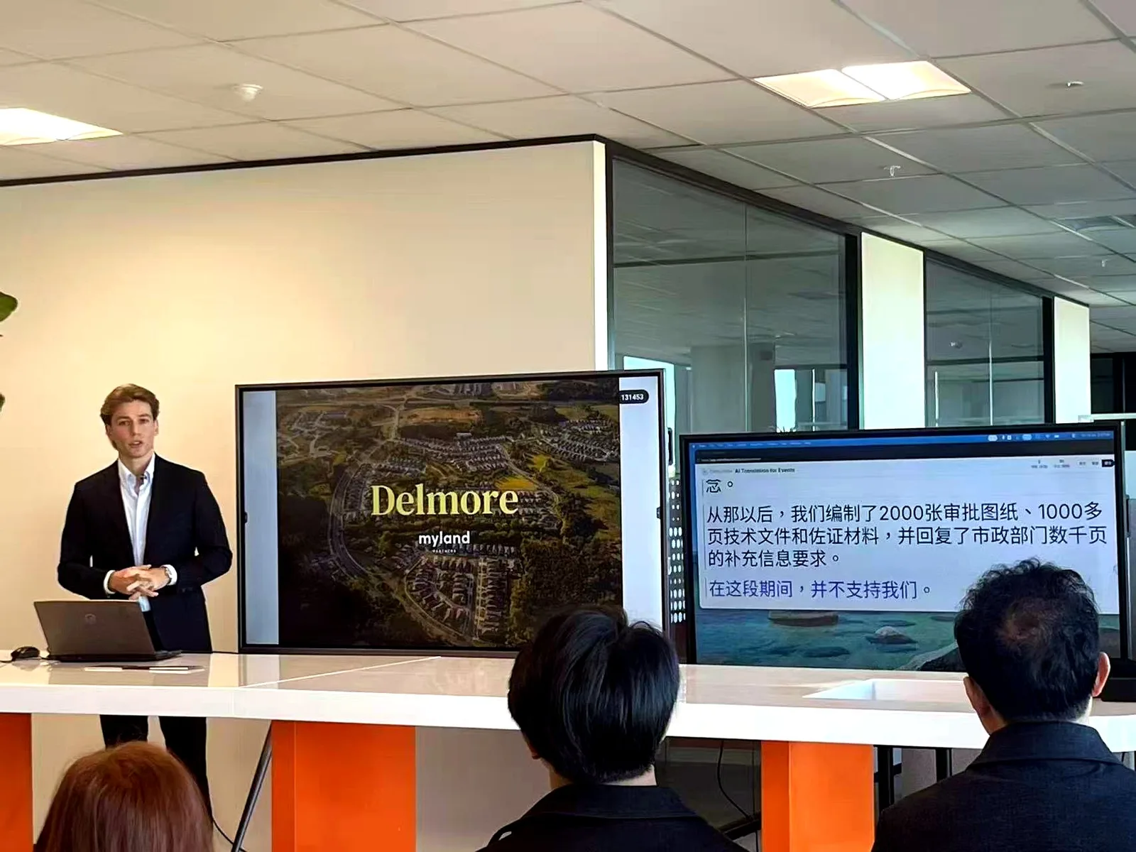 A My Land presenter introducing the Delmore development to a Chinese-speaking audience, with Orato Flow’s live Chinese translation on the screen beside the speaker.