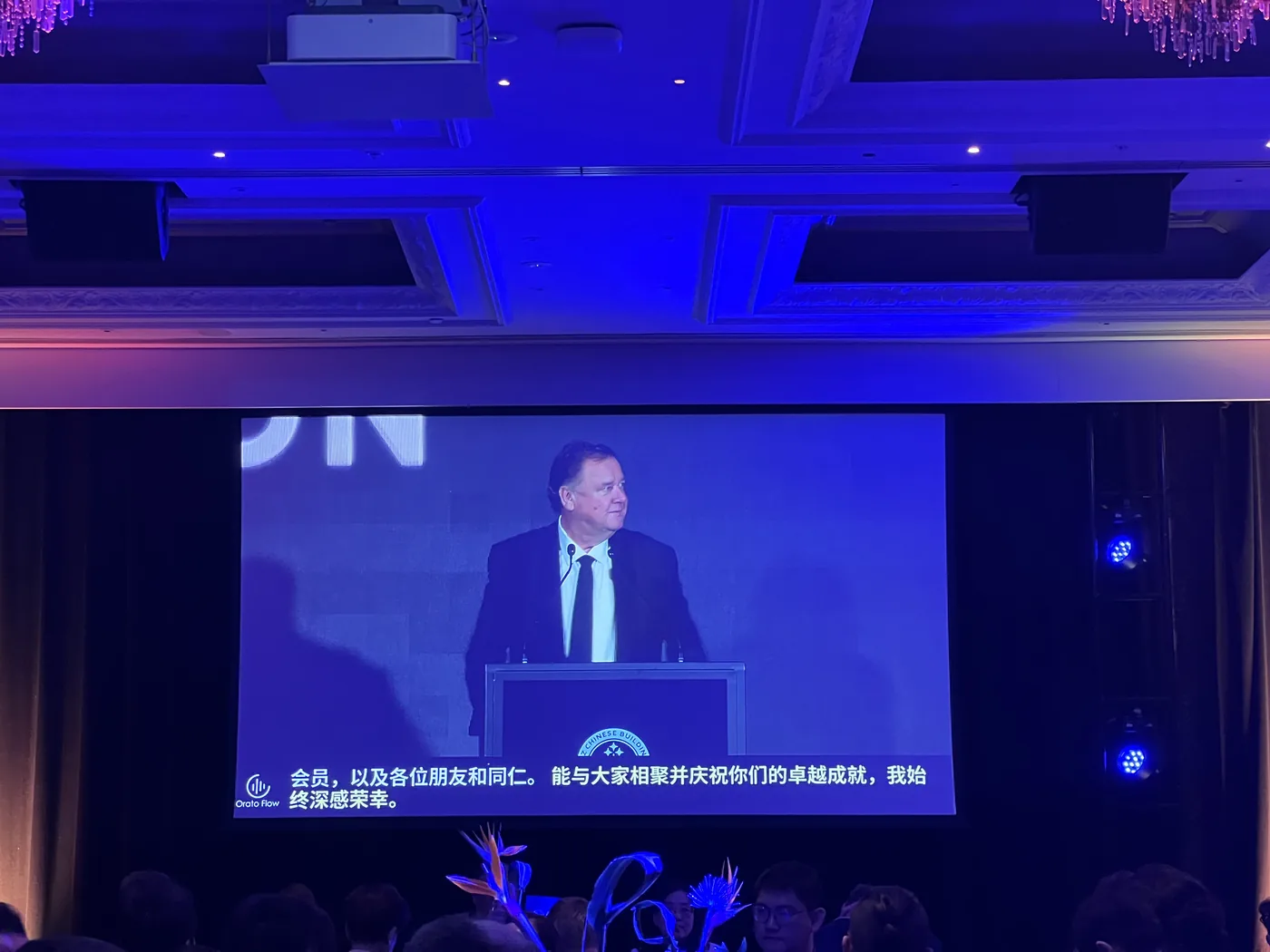Peter Thompson, Managing Director of Barfoot & Thompson, speaking at the NZCBIA lectern on the main screen with live Chinese captions beneath.