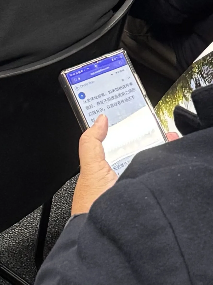 An attendee following the live Chinese translation on a phone held in their lap during the presentation.