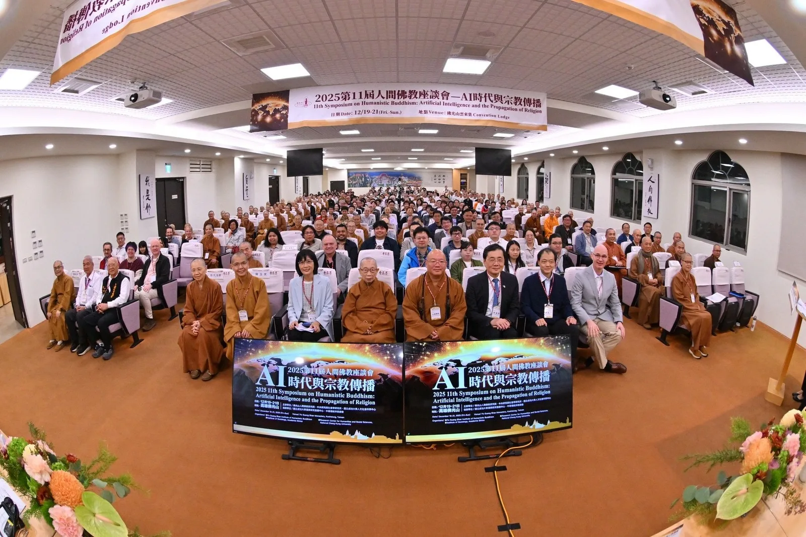 A full-audience group photo at the 11th Symposium on Humanistic Buddhism, the event banner and twin screens behind the delegates.