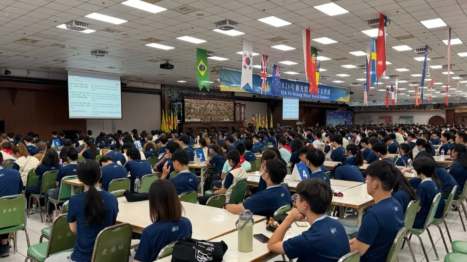 A wide view of the summit hall with the 2026 Fo Guang Shan Youth Summit banner on stage and live captions on the side screens.